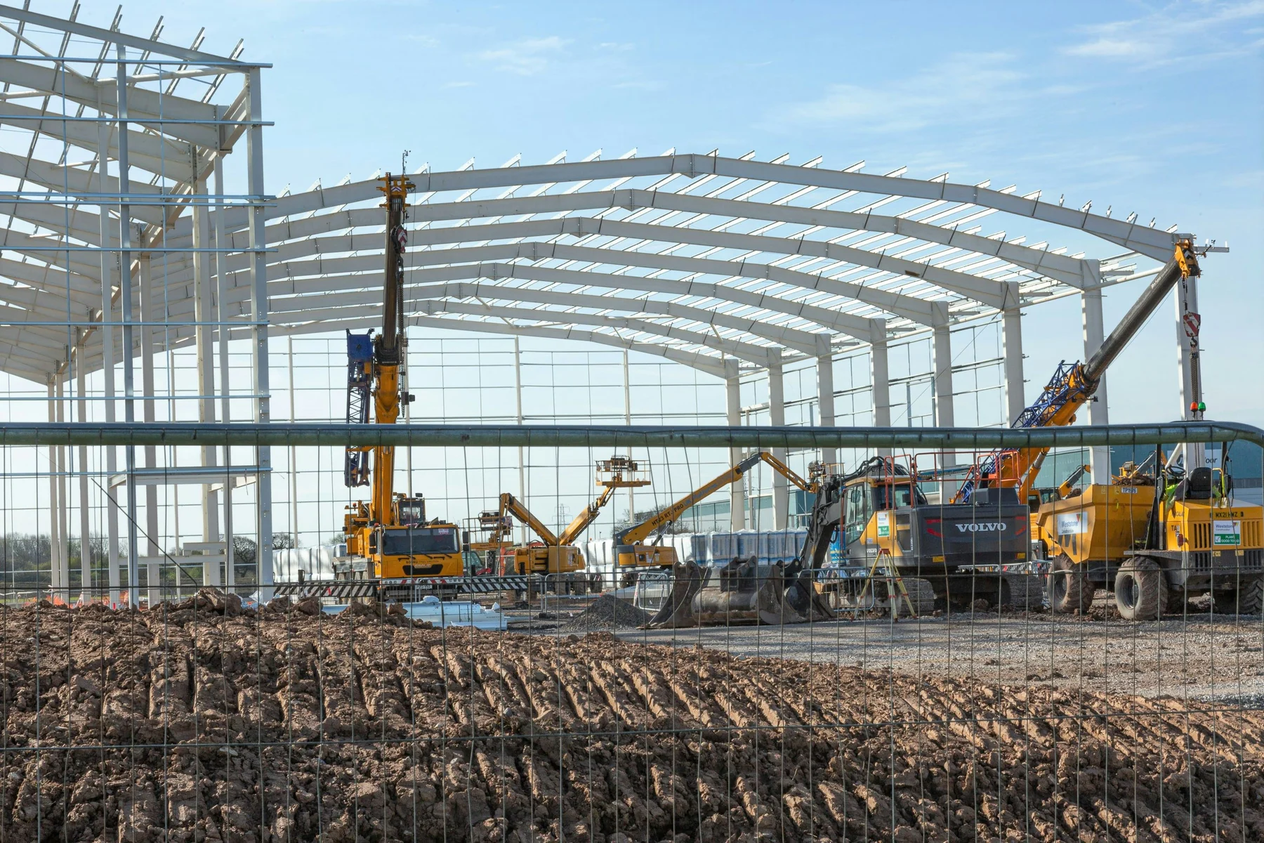 Illustrative photo of an arched steel-building frame under construction with lifting equipment
